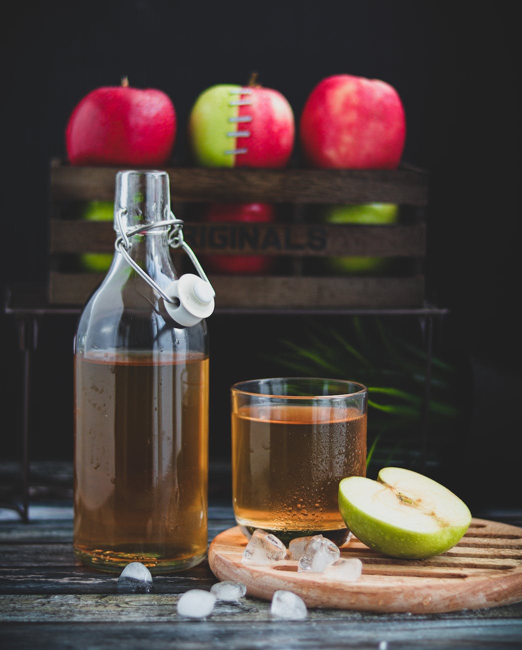 a glass bottle with brown liquid beside a glass of cold drink