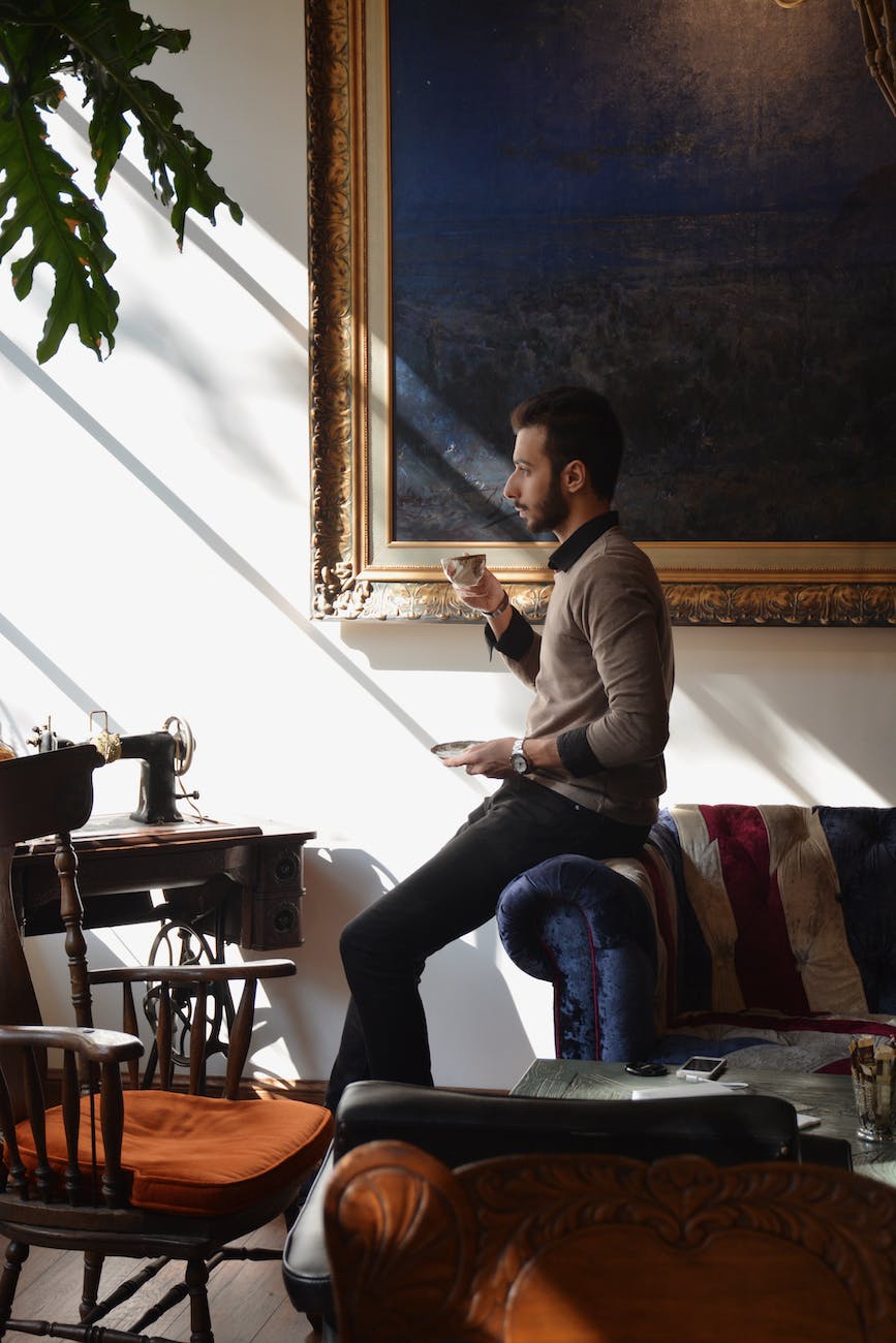 man sitting on a sofa armrest with a tea cup in hand