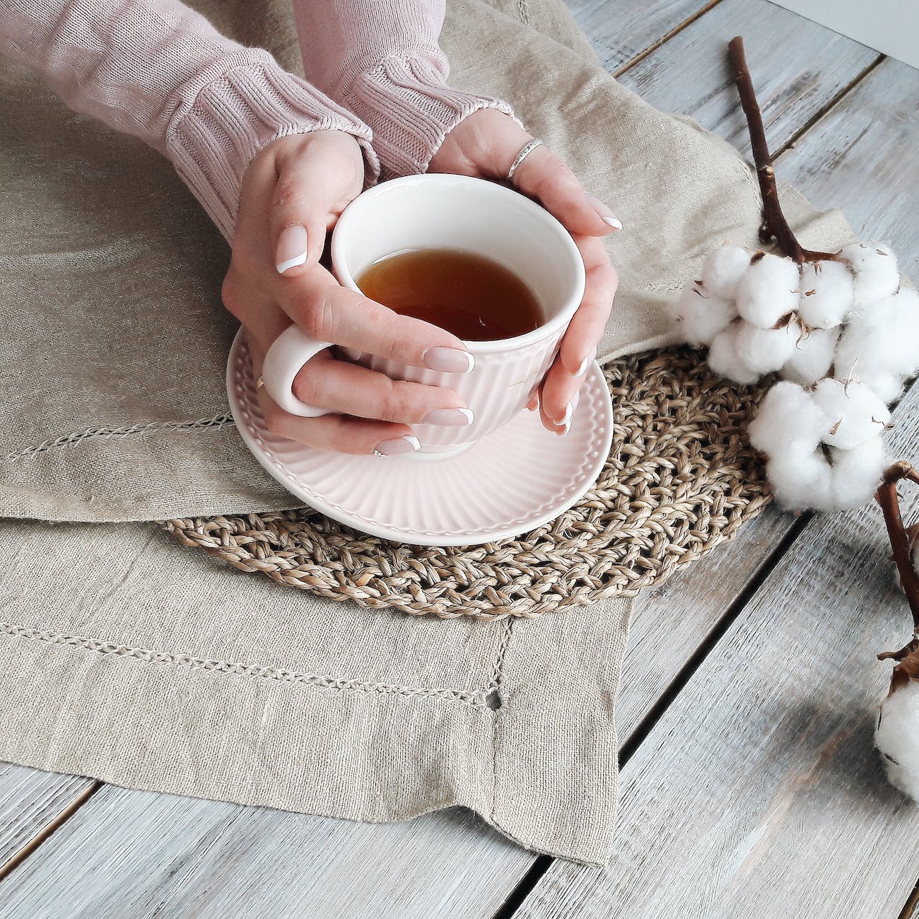 person holding white ceramic teacup with brown liquid