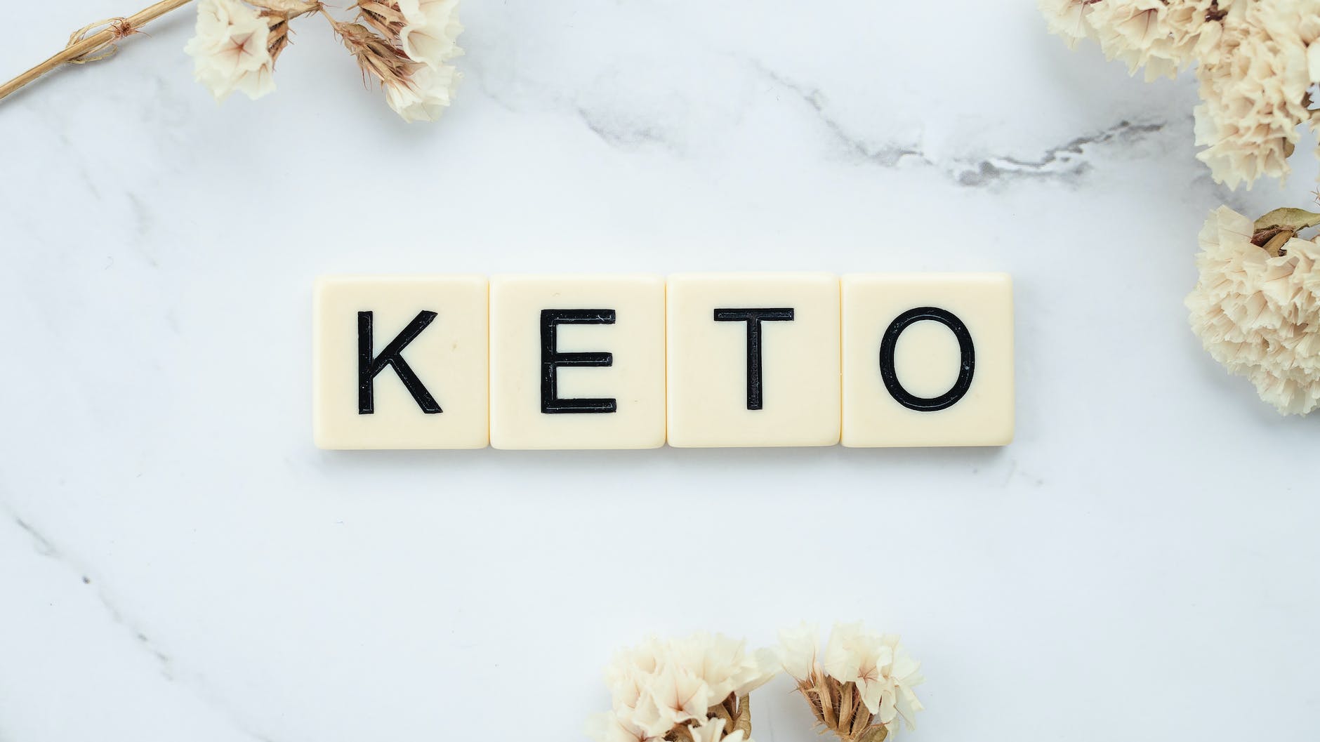 scrabble tiles surrounded by white flowers on a marbled surface