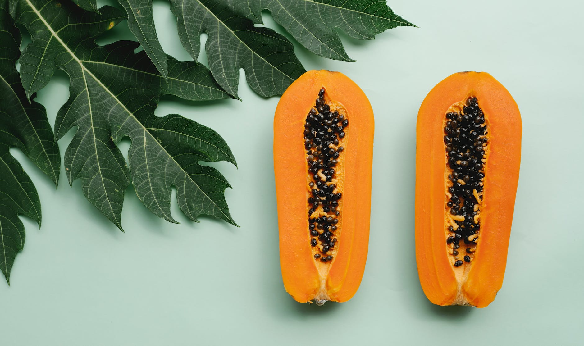 halves of papaya on green background