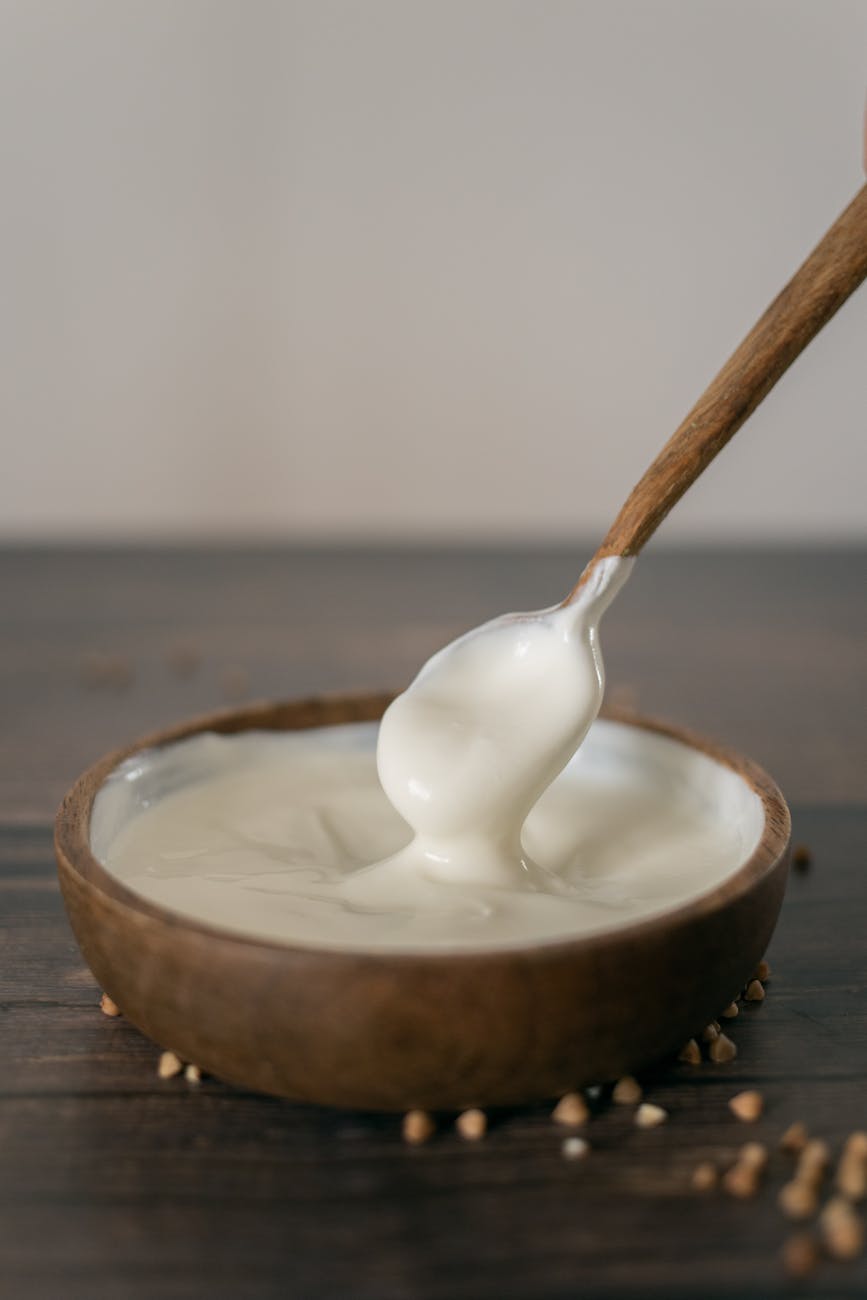 wooden bowl of sour cream with spoon on table