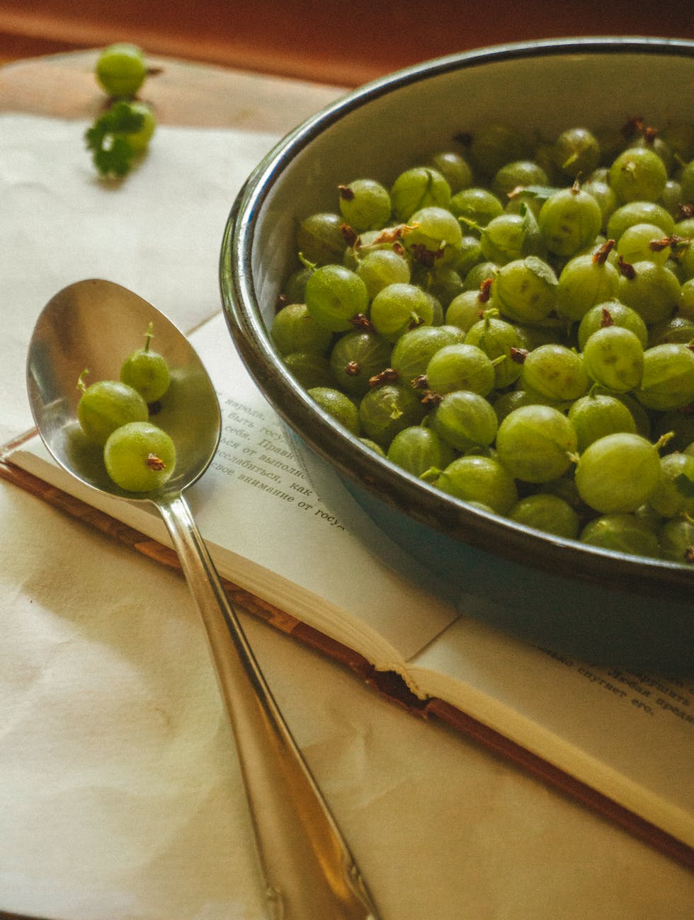 green gooseberry fruits in a bowl and spoon