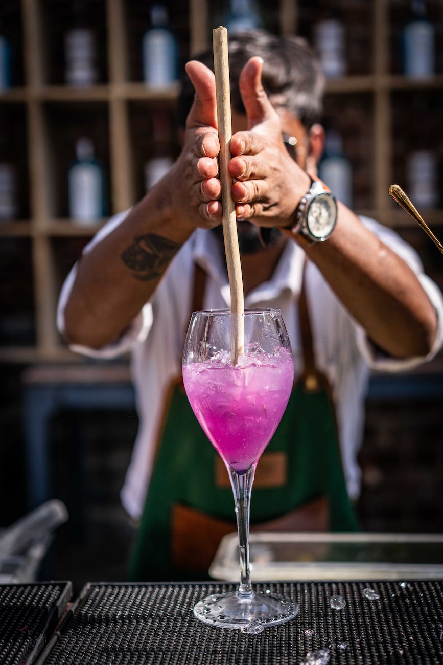 person preparing a beverage in a stem glass