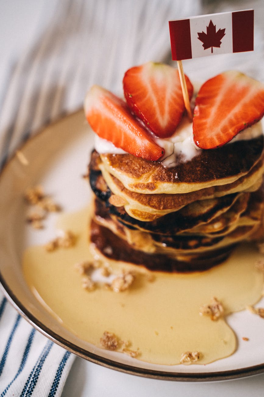 close up photo of a stack of pancakes with a canadian flag on top