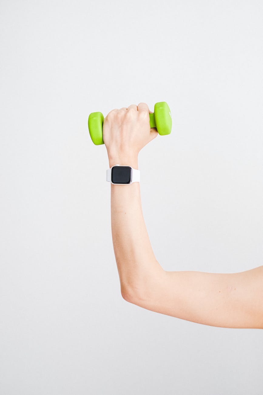 person wearing white apple watch while holding green dumbbell